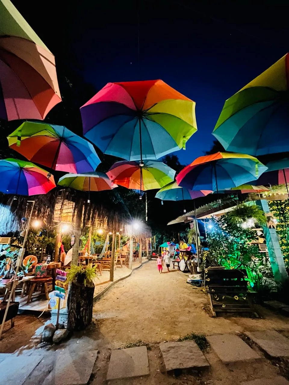 Caminho sob os guarda-chuvas coloridos do Dedo de Moça Café da Roça à noite